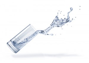 Glass with spilling water splash. Side view. On white background.